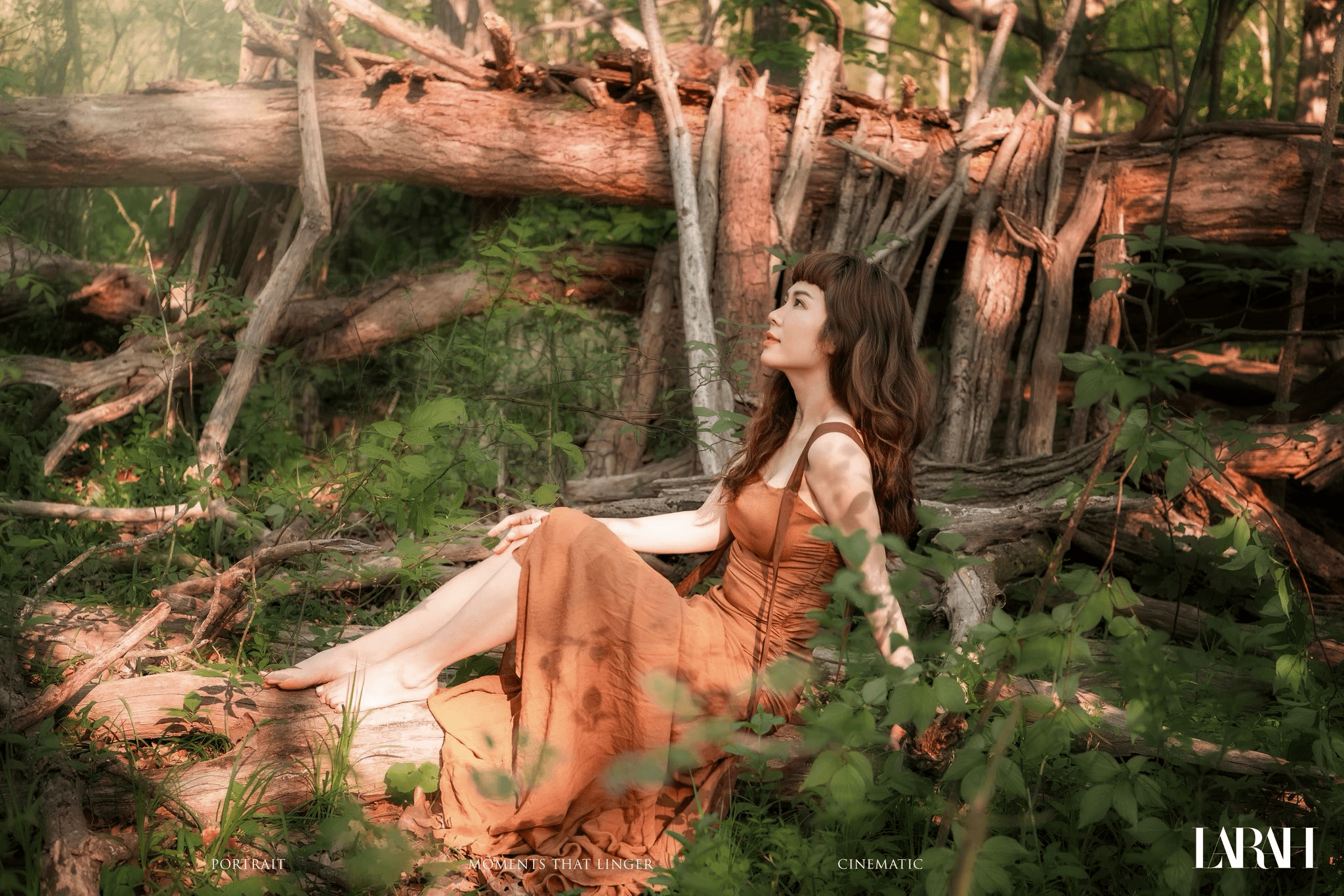 Woman in an orange dress seated in a forest