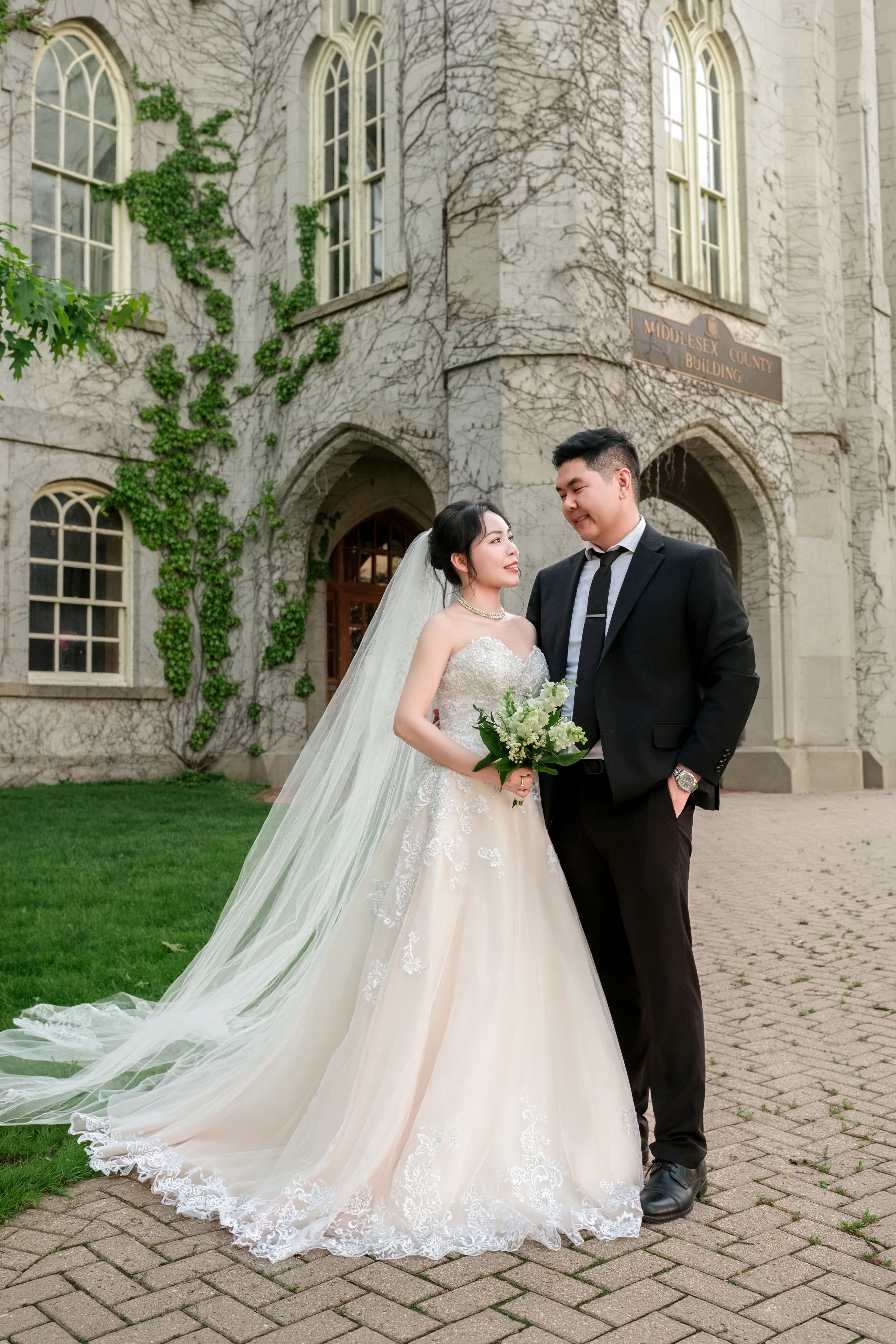 Bride and groom standing side by side at the ivy-framed castle entrance.